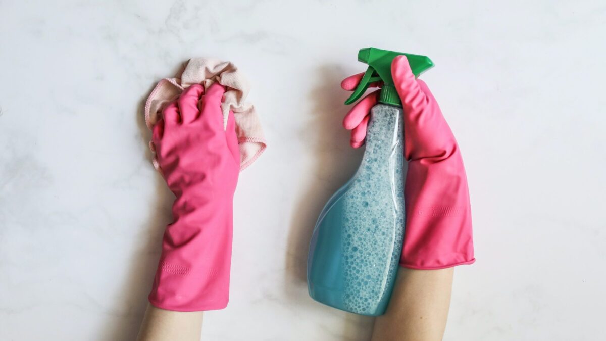 Exterminator wearing gloves and using pest control spray.