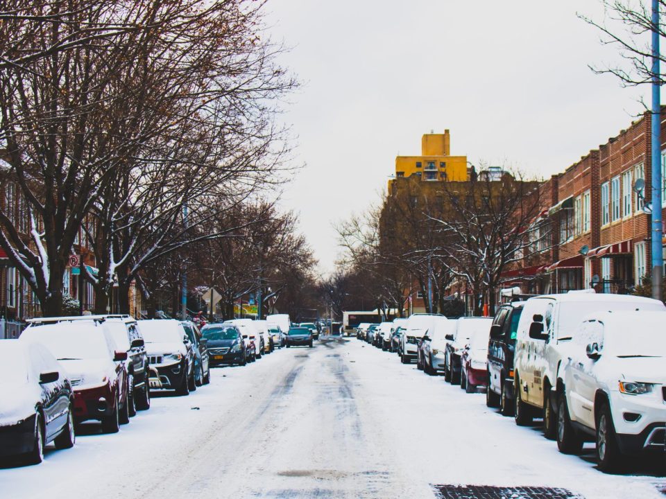 Snowy street lined with cars