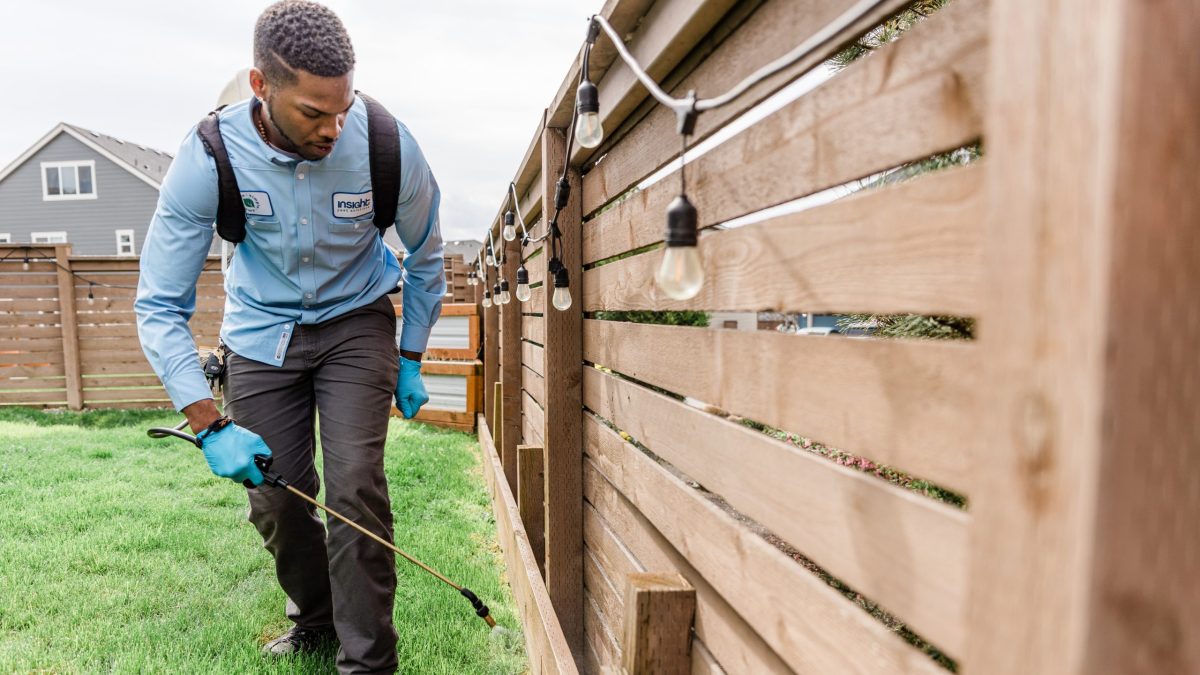 Insight Pest Technician spraying on a fence